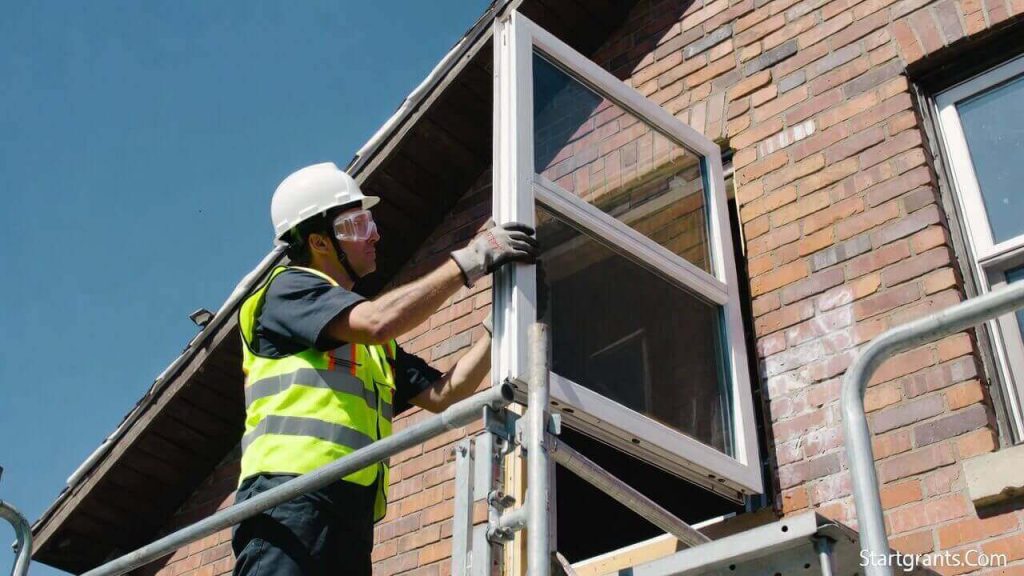 A contractor performing a deep energy retrofit on an aging house by installing high-efficiency windows.