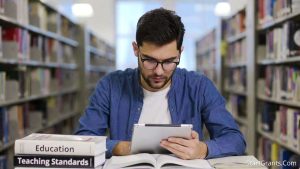 A focused graduate student reviewing the FAFSA teacher certification loophole requirements on a tablet in a university library.