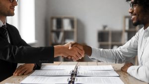 Diverse business partners shaking hands over contract documents representing MBE certification