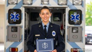 A proud paramedic student holding a scholarship award certificate from an EMS foundation alongside an ambulance.