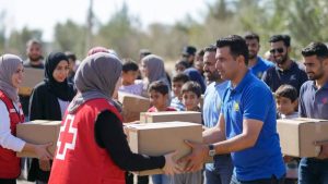 Diverse volunteers from different faith backgrounds (including Muslims and Christians) working together to distribute food boxes to families in need.