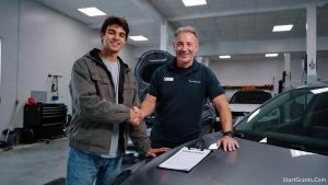 An automotive student shaking hands with a dealership service manager securing a corporate sponsorship