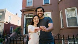 A happy couple holding keys to their new house bought with first time home buyer grants NY.