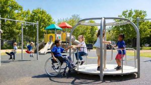 Children of all abilities, including a child in a wheelchair, playing together on a colorful, ADA-accessible school playground funded by special education grants.