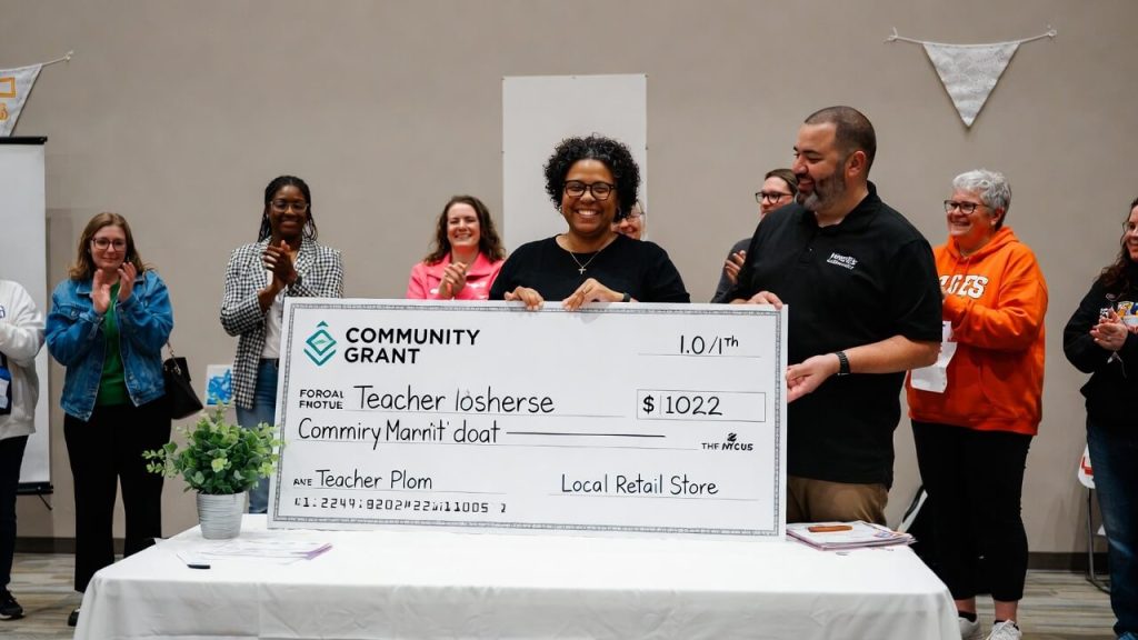 Teacher receiving a community grant donation from a local retail store manager.