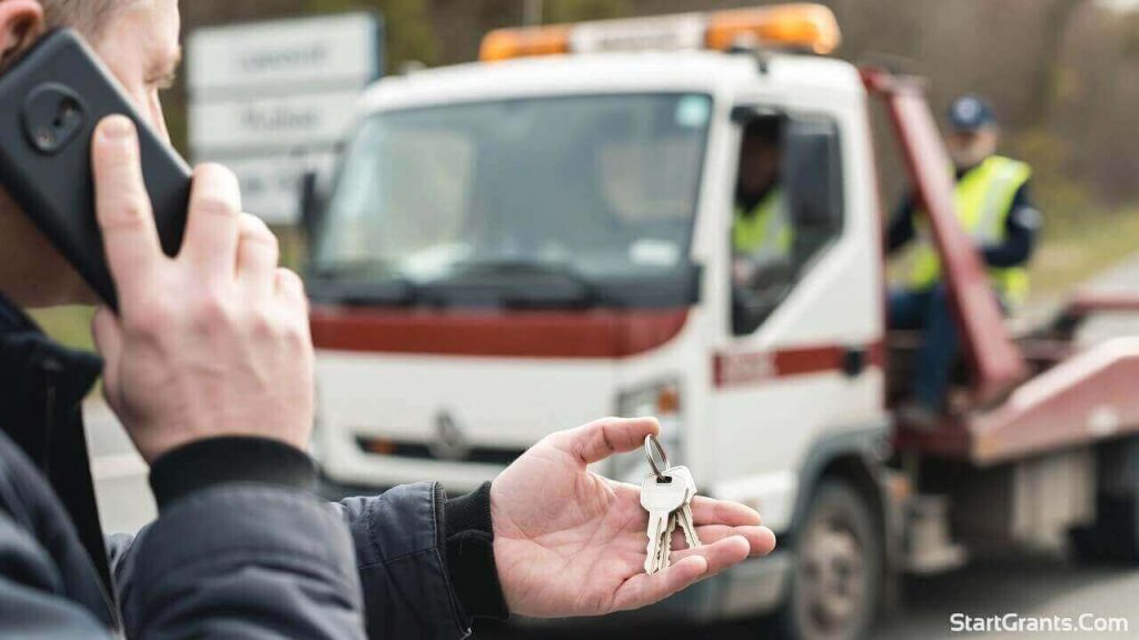 A driver handing over car keys to a tow truck driver before calling their auto insurance company to cancel the policy.