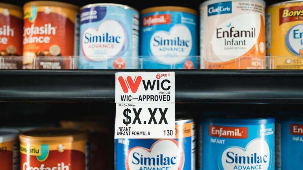 A grocery store shelf label with the "WIC Approved" logo next to a can of infant formula.