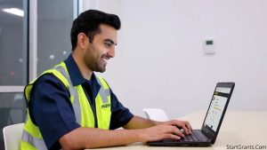 An adult worker in a retail uniform happily reviewing an online GED course on a laptop provided by their employer.