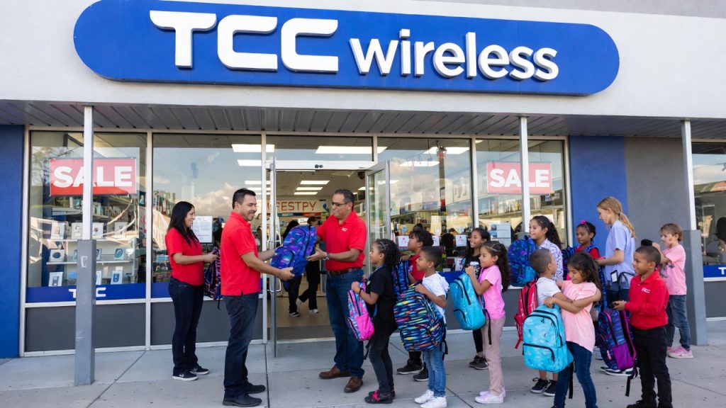TCC Wireless store employees handing out free backpacks to children.