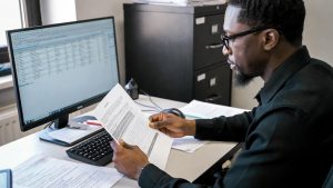 Minority business owner reviewing federal government contract documents for 8(a) program.