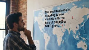 Small business owner looking at global export map funded by STEP grant.
