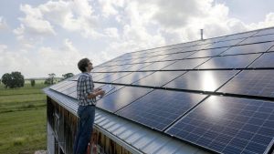 Rural business owner inspecting solar panels funded by USDA REAP grant.