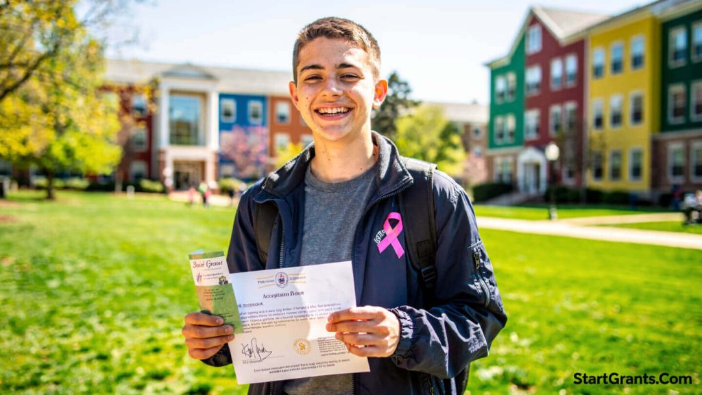 A young college student and cancer survivor smiling confidently on campus while holding a scholarship award letter.