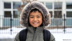 A smiling student wearing a new winter coat and backpack, representing the benefits of the Chickasaw Nation clothing grant.