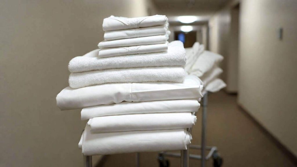 A stack of clean white hotel towels and linens ready to be donated to a local charity