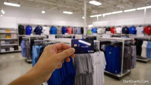 A parent holding a prepaid Visa card used to purchase approved clothing and shoes for the Chickasaw Nation grant.
