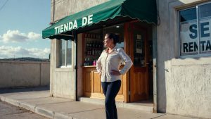 Confident Hispanic woman business owner standing in front of her small business representing success