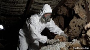 A hazardous materials professional inspecting toxic attic insulation before a WAP weatherization upgrade.