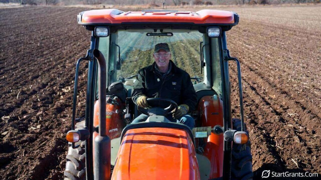 A military veteran sitting proudly on a new Kubota tractor awarded by the Farmer Veteran Coalition.
