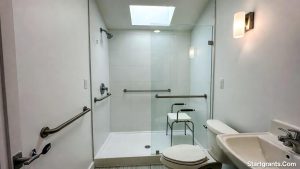 A modern, accessible bathroom featuring a roll-in shower and grab bars funded by VA benefits.