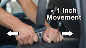 Hands performing the "Inch Test" on a car seat base to ensure it is tight enough.