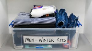 An organized homeless shelter donation box filled with new socks, clean clothes, and toiletries.
