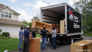 Volunteers loading donated wooden kitchen cabinets into a Habitat for Humanity ReStore box truck during a home remodel.