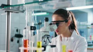 A science student is using a microscope in a laboratory to meet the eligibility requirements for an AFTE forensic scholarship.