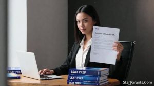 A focused pre-law student reviews a law school admission and merit scholarship offer letter while calculating tuition costs on a laptop.