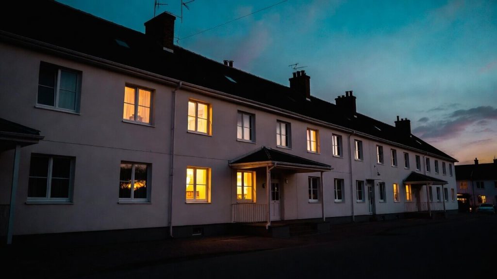 Exterior view of a modern transitional housing building with warm lighting, representing a safe, stable living environment.
