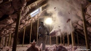 A contractor installing free attic insulation funded by the federal Weatherization Assistance Program.