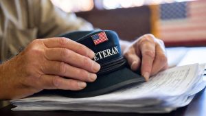 Military veteran holding SSVF and HUD-VASH housing assistance application documents.