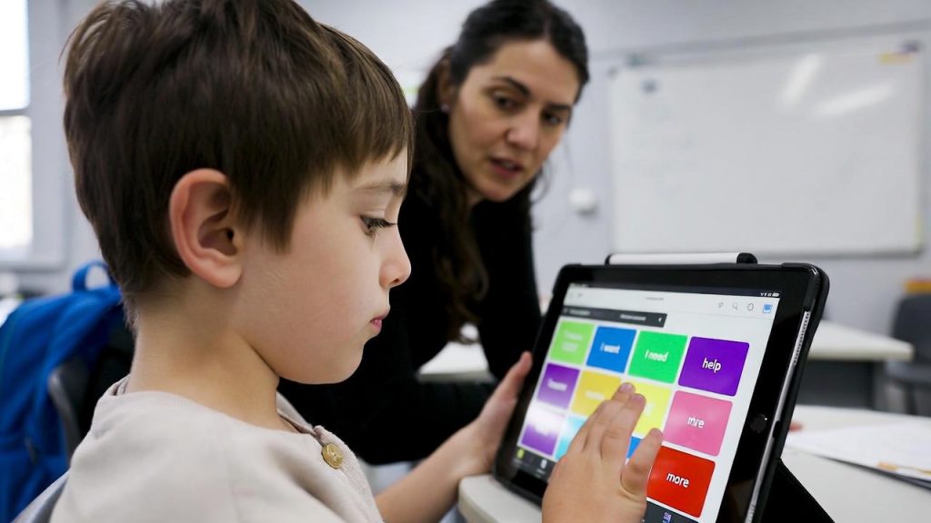 Special education student using an AAC communication app on a tablet with teacher.