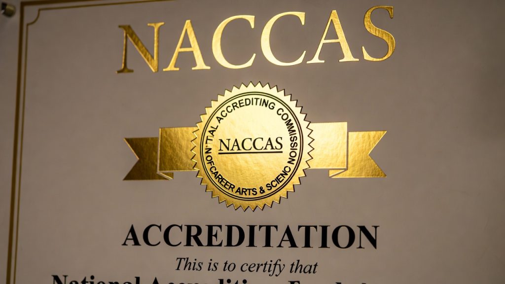 Close up of a NACCAS accreditation certificate on a wall.