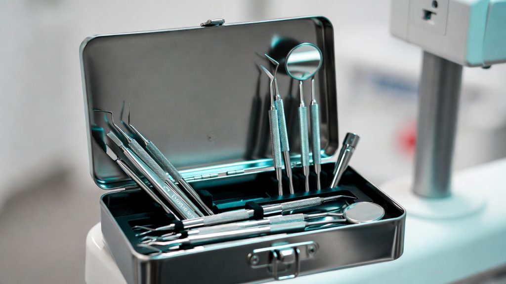 A close-up of a professional dental hygiene instrument kit with scalers and mirror.