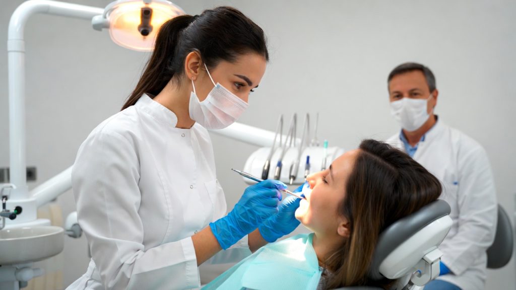 A dental student performing a checkup on a patient under the supervision of a professor.