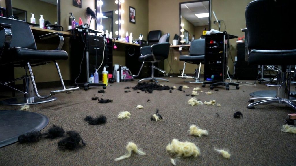A messy salon floor with un-swept hair and cluttered stations.