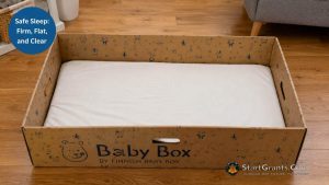 A Finnish-style cardboard baby box set up safely on the floor with a firm mattress pad and no loose bedding.